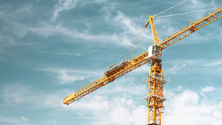 An industrial crane rises against a partly cloudy sky.