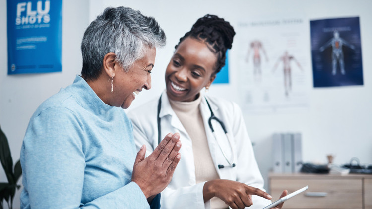 A doctor goes over test results with her patient. They are both smiling